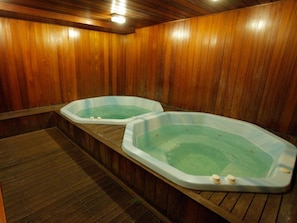 Two hot tubs in a wooden room with a wooden floor.