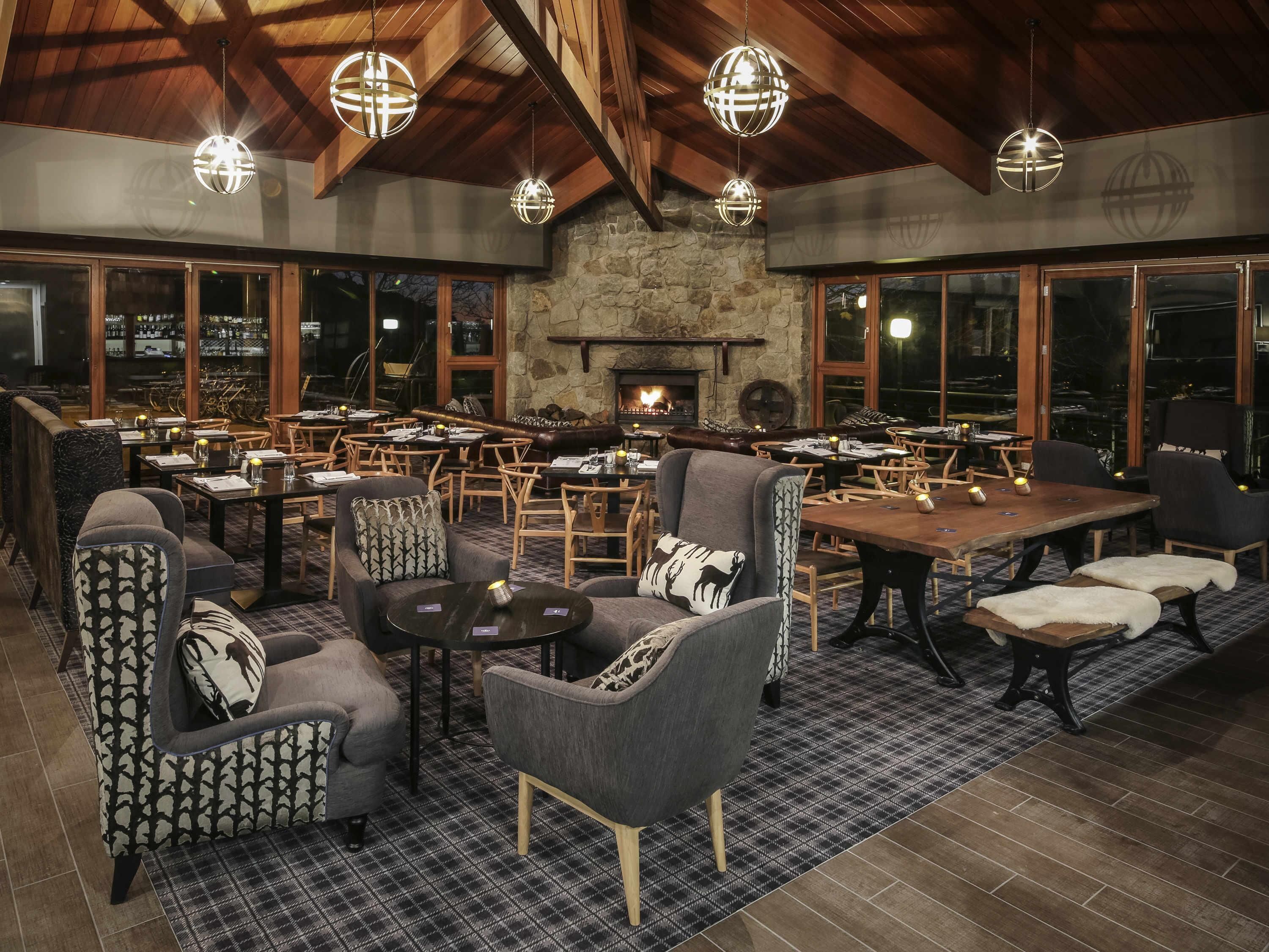 A spacious indoor area with multiple seating arrangements, a stone wall, and a fireplace.