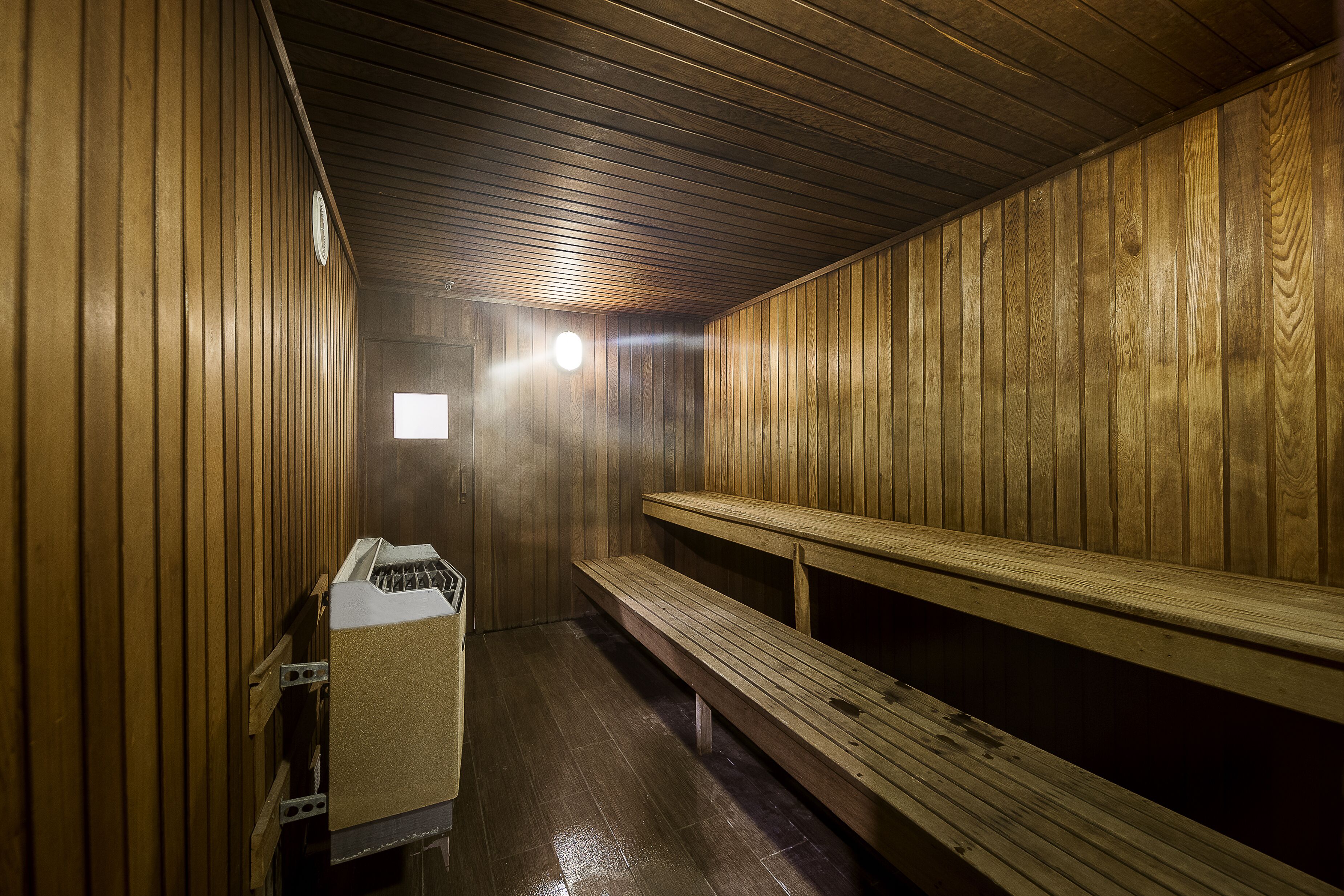 Un sauna avec des murs et des bancs en bois.