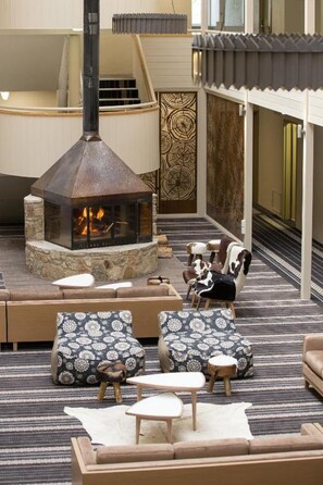 Una zona de estar acogedora con chimenea de piedra, asientos estampados y vista al interior.