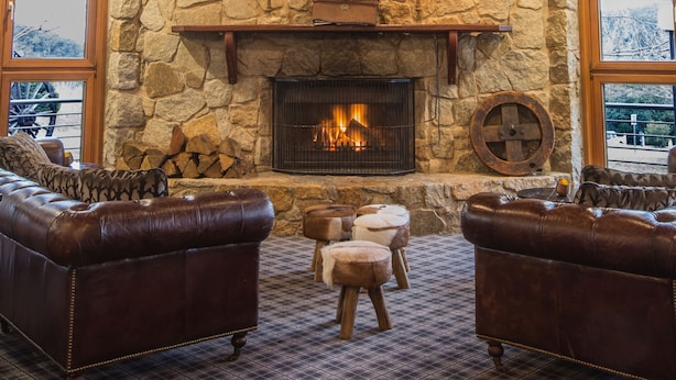 A cozy interior with a stone fireplace, leather sofas, and wooden beams. - The Sebel Pinnacle Valley Resort (Merrijig)