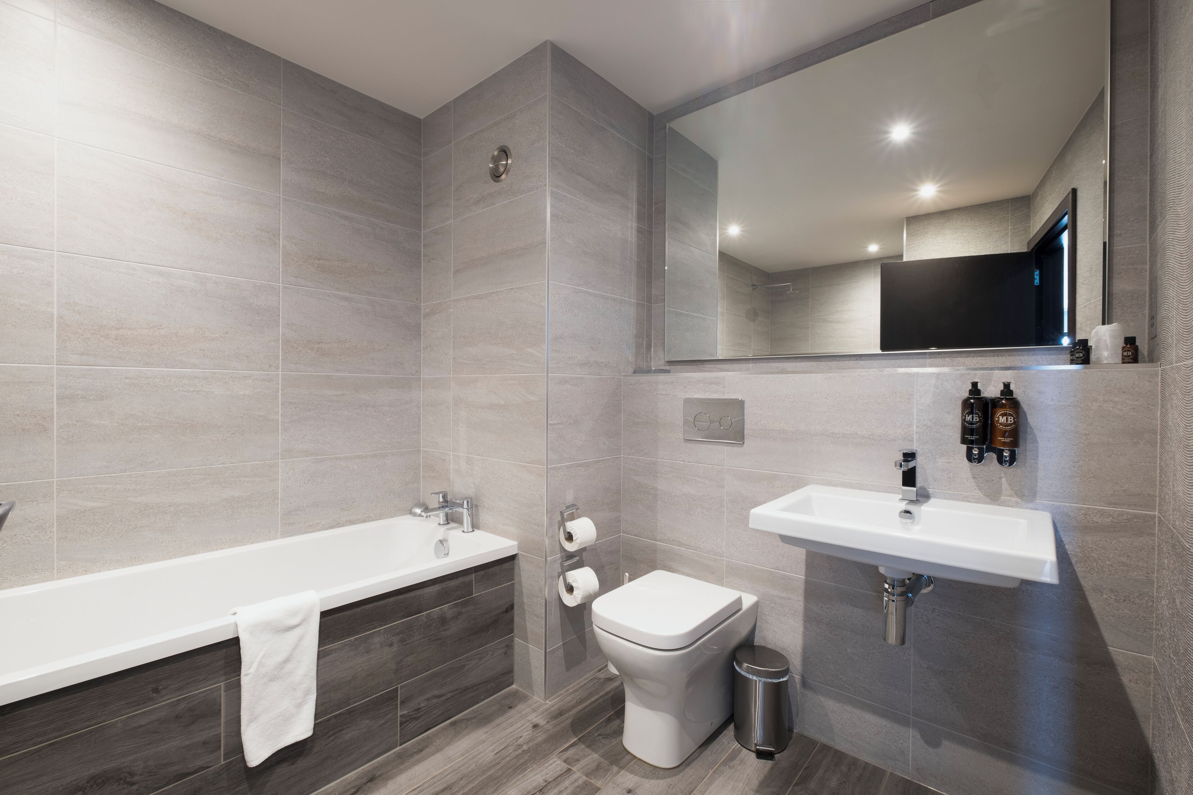 Une salle de bain moderne équipée d’une baignoire, de toilettes, d’un lavabo et d’un miroir.