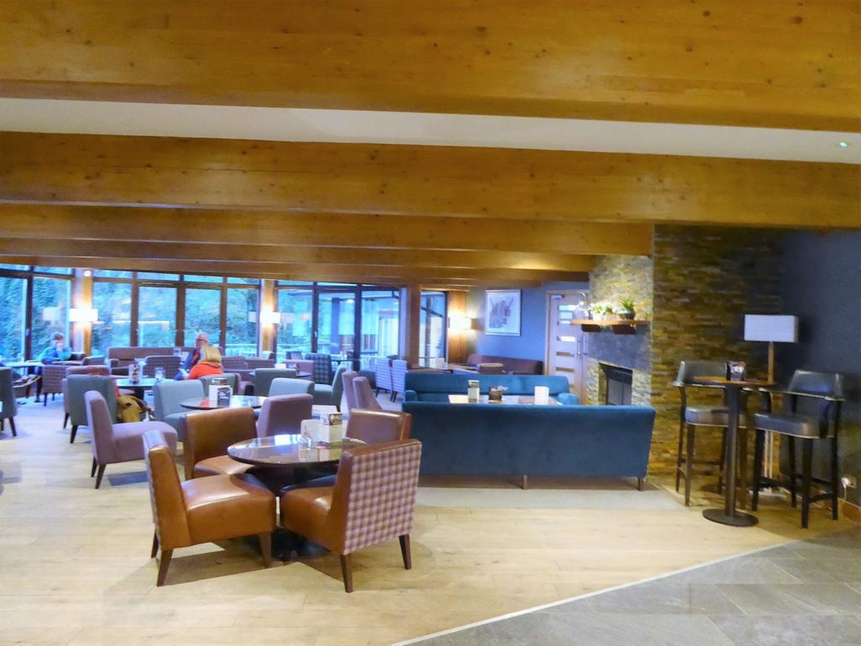 A spacious indoor area with multiple seating arrangements, including round tables and chairs, and a fireplace.