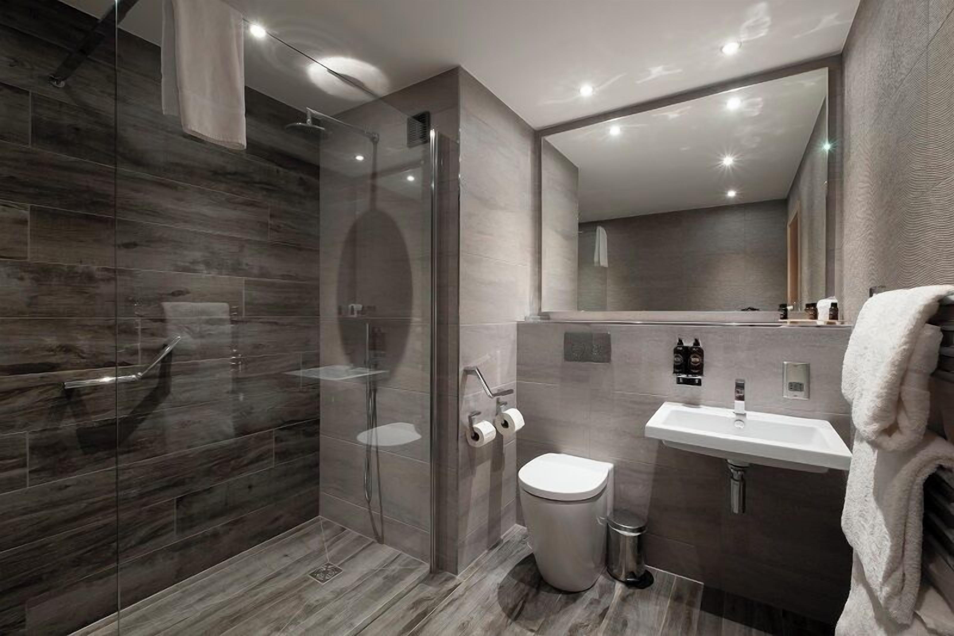 A modern bathroom with a glass-enclosed shower, a toilet, and a sink.