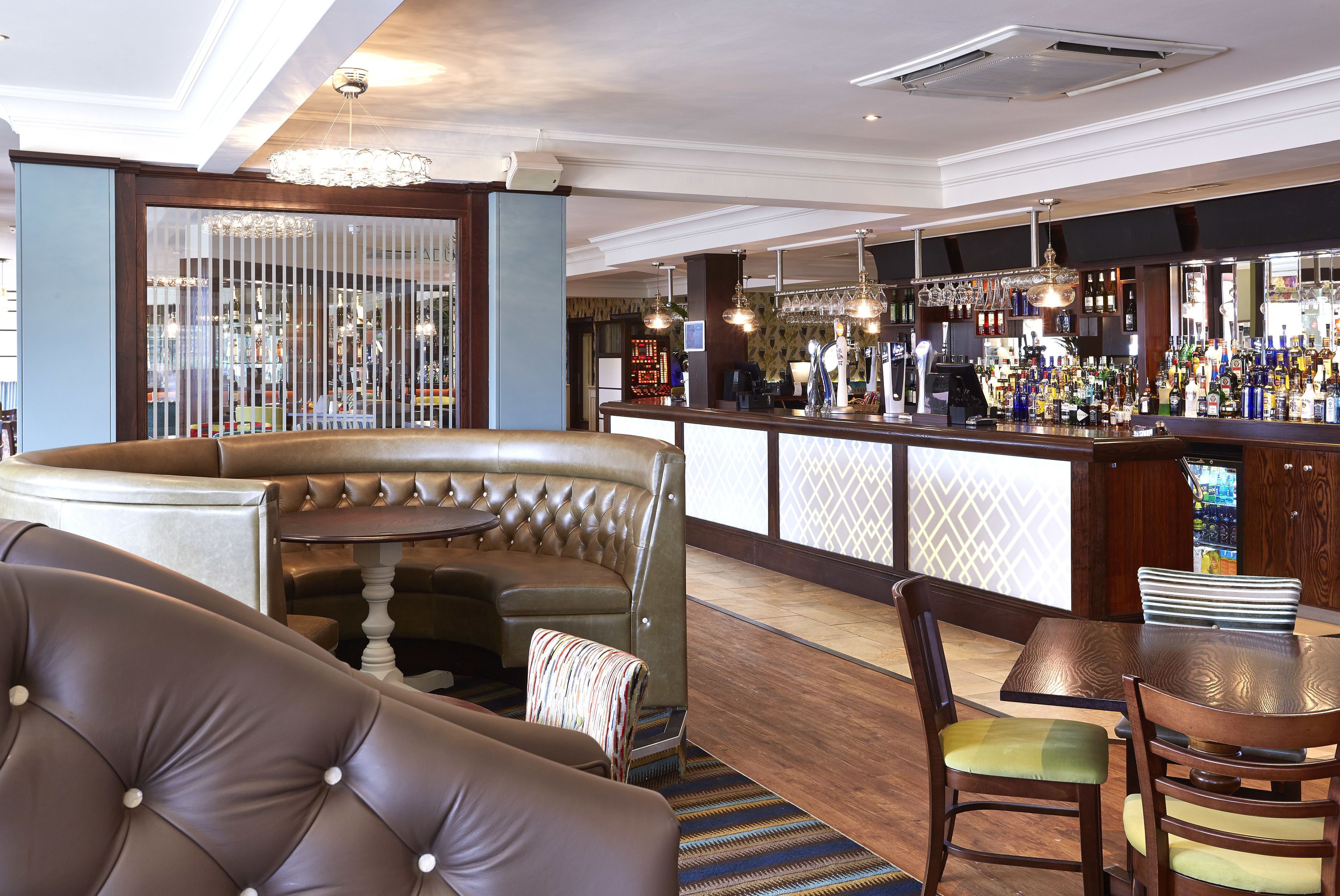 A bar area with a bar counter, seating, and a variety of bottles.