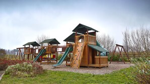 Ein Spielplatz aus Holz mit Rutschen und Klettergerüsten.