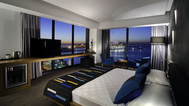 A modern hotel room with a large bed, a TV, a desk with a computer, and a view of the sea. - Ilayda Avantgarde Hotel (Kusadasi)