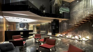 A modern lobby with a reception desk, seating area, and a staircase. - Ilayda Avantgarde Hotel (Kusadasi)