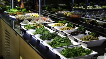 A buffet with various food options including salads, greens, and olives.