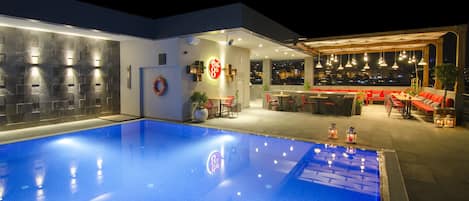 A modern hotel with a swimming pool, outdoor seating, and city views.