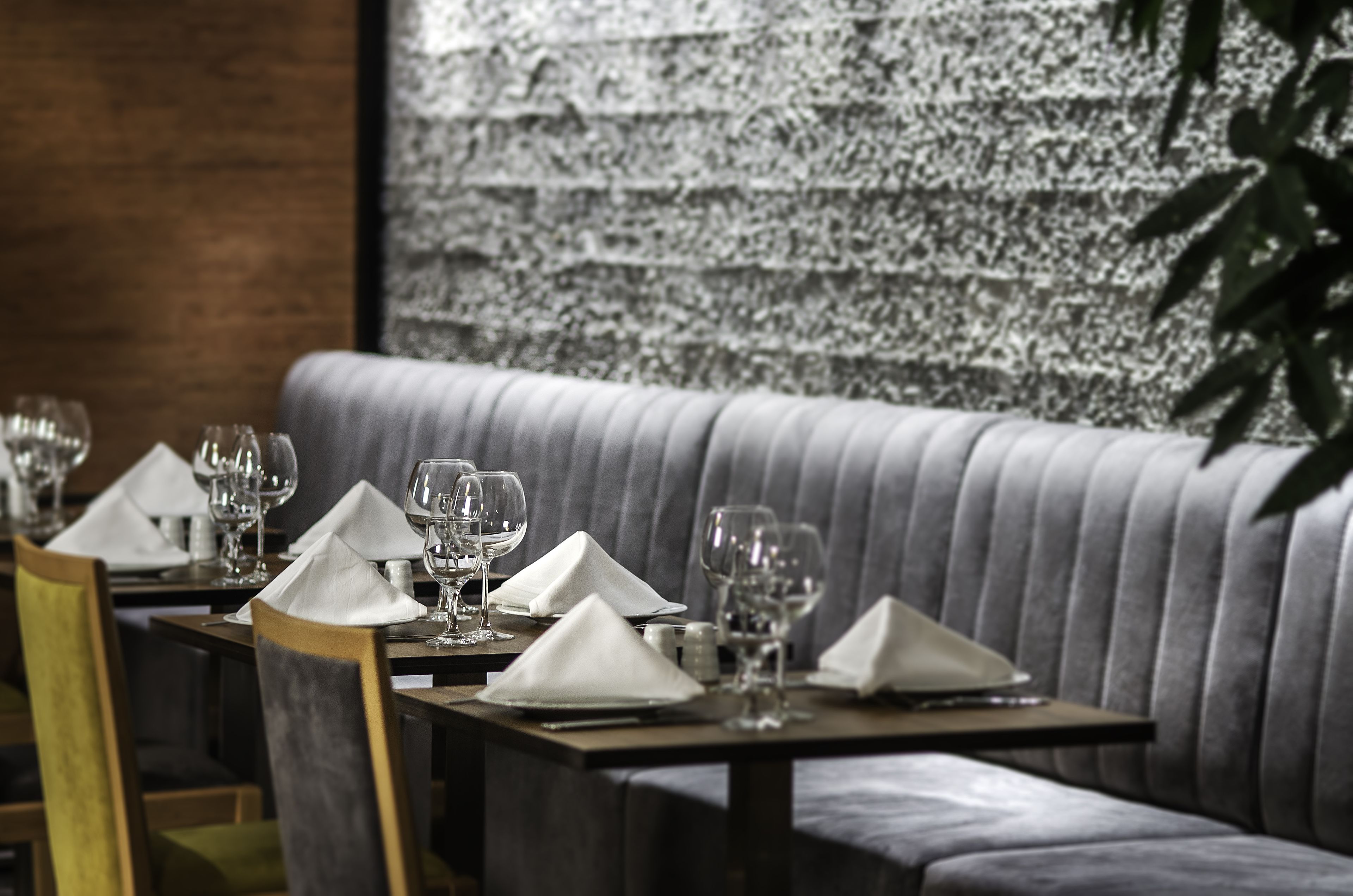 A dining area with tables set for a meal, featuring neatly arranged wine glasses and napkins.