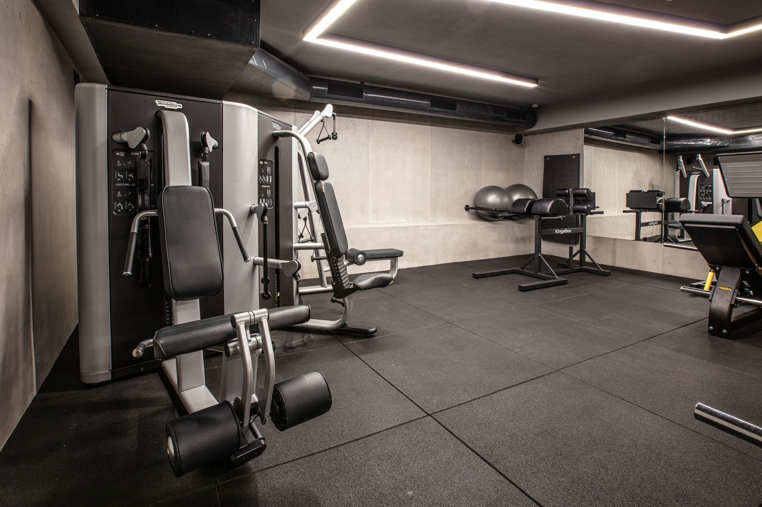 Une salle de sport moderne équipée de divers appareils d’exercice, notamment un banc de musculation, des haltères et un appareil d’aviron.