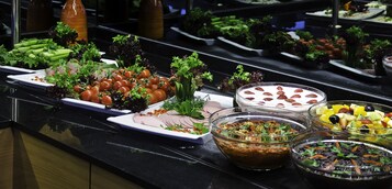A buffet with various dishes including vegetables, fruits, and salads.