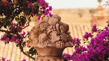A stone urn with a floral and fruit design, surrounded by vibrant bougainvillea flowers.