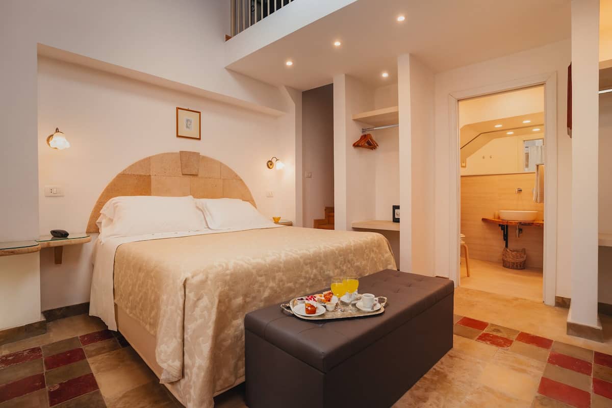 A hotel room with a bed, bedside table, and a tray with breakfast items.