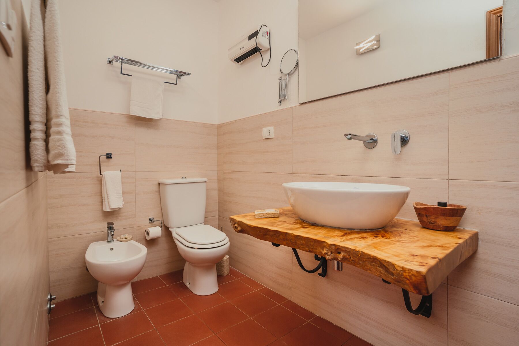 A bathroom with a toilet, bidet, and a large sink on a wooden countertop.