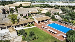 Vista aérea de un resort con piscina, mobiliario exterior y arquitectura tradicional.