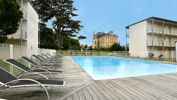 Une piscine avec des chaises longues et une terrasse en bois.