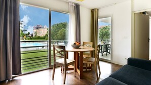 Un salon moderne avec un coin repas, de grandes portes-fenêtres coulissantes donnant sur une piscine et un jardin, et une vue sur un bâtiment historique.