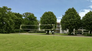 Zona verde con red de voleibol, árboles y un edificio con un letrero que dice 'Chateau'.