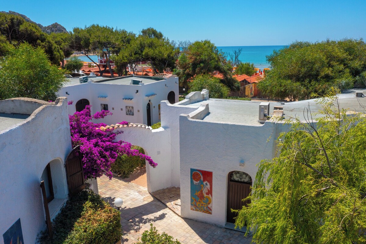 A coastal village with white-washed buildings, a narrow street, and a view of the sea.