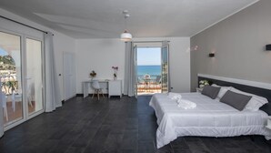 A modern bedroom with a large bed, a desk, and a view of the sea. - Baia D'Oro Hotel (Licata)