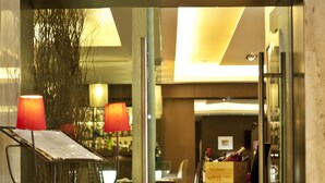 A hotel lobby with a reception desk, chairs, a table with a box, and a glass partition. - TURIM Restauradores Hotel (Lisbon)