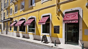 A yellow building with multiple storefronts, including a hotel and restaurants named "Glory Ristorante". - TURIM Restauradores Hotel (Lisbon)
