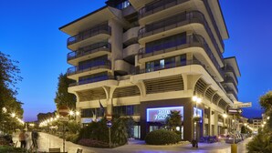 A multi-story hotel with balconies and a neon sign indicating it is Hotel Fonza. - Hotel Fonzari (Grado)