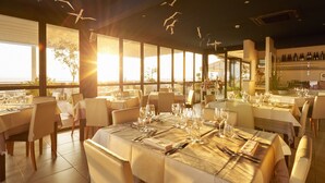 A restaurant with tables set for dining, large windows, and a view of the outdoors. - Hotel Fonzari (Grado)