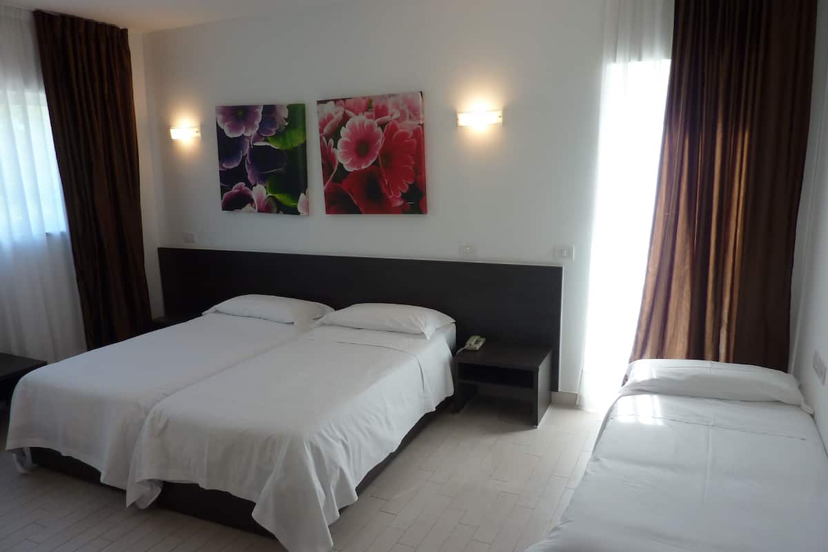 Ein Hotelzimmer mit zwei Einzelbetten, einem Nachttisch mit Telefon und Wandleuchten.