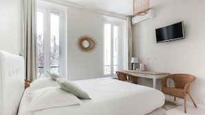 A bedroom with a bed, a desk, a chair, a TV, and a window with curtains. - Central Hotel (Avignon)