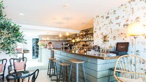 A bar area with stools, a counter, and a variety of bottles and glasses. - Central Hotel (Avignon)