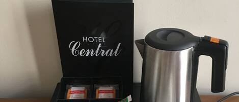 A coffee station with a coffee maker, two cups, and a box labeled "HOTEL Central".