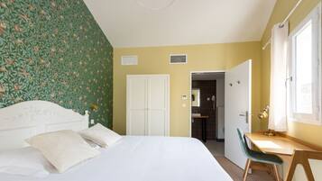 A bedroom with a bed, a desk, and a chair. There is a door leading to a bathroom.