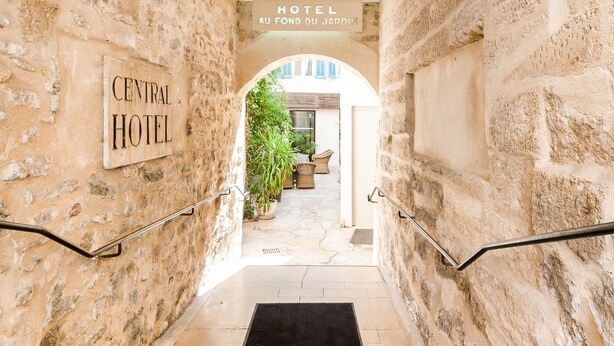 A stone-walled hallway leading to a courtyard with a sign reading "HOTEL CENTRAL AVIGNON." - Central Hotel (Avignon)