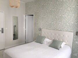 Un dormitorio con una cama grande, un espejo y una puerta.
