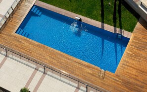Relax by the pool surrounded by a walkway and a wooden deck.
