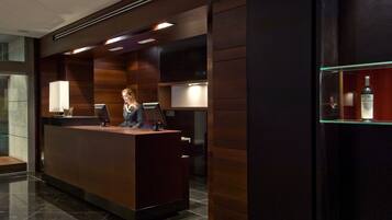 A reception desk with a dark wood finish, two computer monitors, and a glass display case with a bottle.