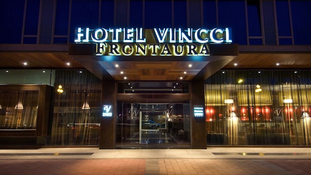 L’entrée de l’hôtel Vincci Frontaura, avec son enseigne lumineuse et sa façade en verre.