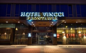 The entrance of Hotel Vincci Frontaura with illuminated signage and a glass facade.