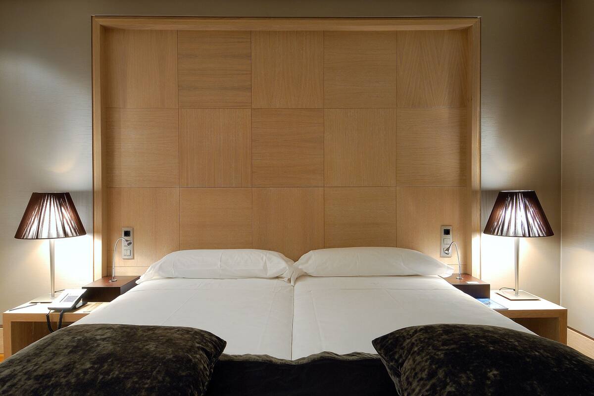 Una habitación de hotel con una cama grande, dos mesitas de noche y dos lámparas.