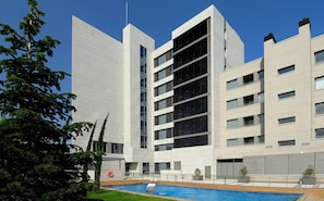 Stunning building with a sleek design, featuring a flat facade and a swimming pool with a wooden deck.