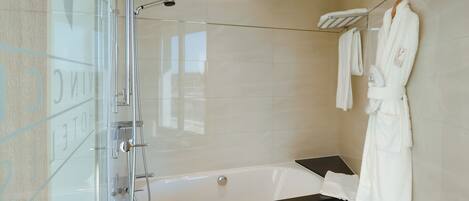 A modern bathroom with a glass-enclosed shower, a bathtub, and a glass door.