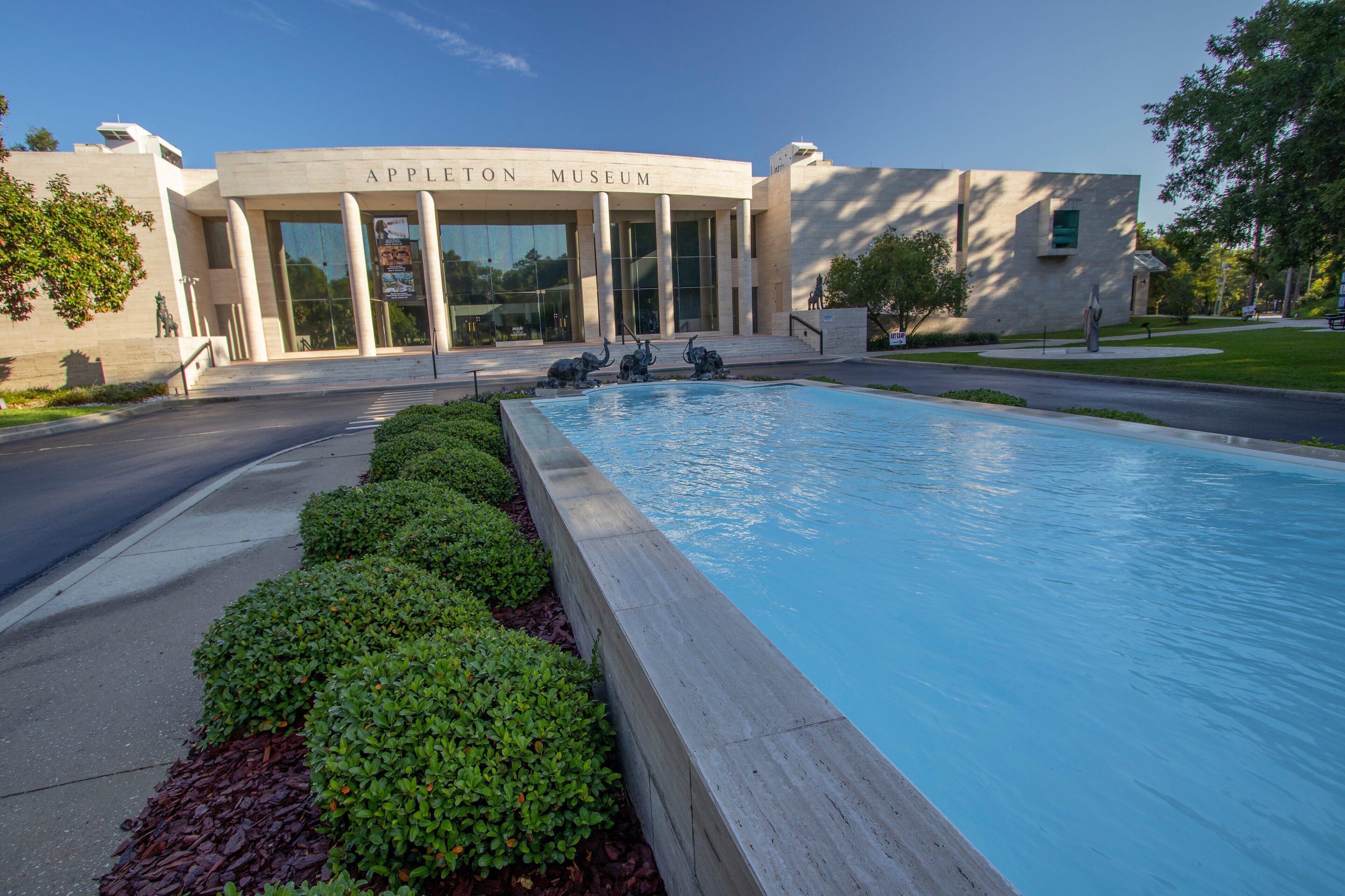 The exterior of the Appleton Museum with a large pool and a well-maintained garden area.