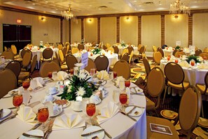 A banquet hall with round tables set for dining, chairs, and chandeliers. - Holiday Inn & Suites Ocala Conference Center by IHG (Ocala)