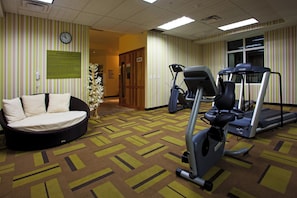 Gimnasio con equipo de ejercicio, un reloj y un cartel que indica su uso exclusivo para huéspedes registrados.