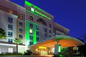 A Holiday Inn & Suites hotel with a modern facade, large windows, and a covered entrance.