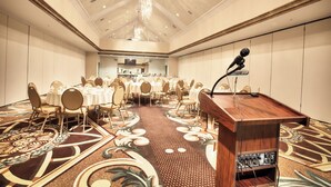 Una sala conferenze con un podio, tavoli e sedie disposti per una riunione.