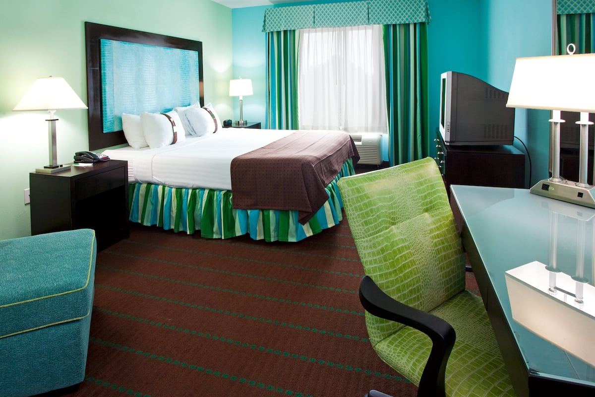 Ein Hotelzimmer mit Bett, Schreibtisch, Stuhl, Fernseher und Lampe.
